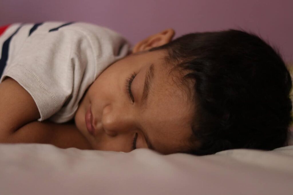 kontya dishela pay karun zopave हसत झोपणारा मुलगा आणि कोणत्या दिशेला पाय करून झोपावे यावरील मार्गदर्शन दर्शवणारे दृश्य